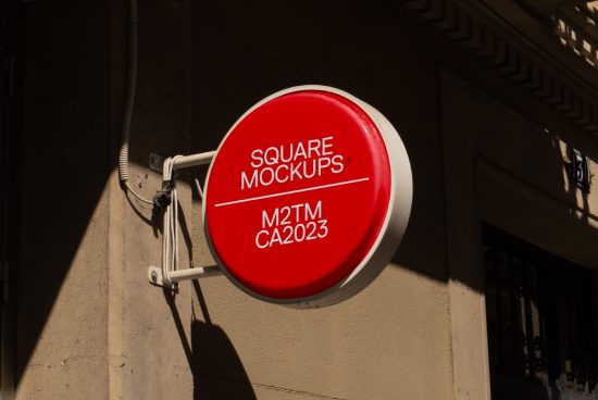Circular storefront sign mockup on sunny facade for outdoor branding designs, featuring editable red surface with shadow details.